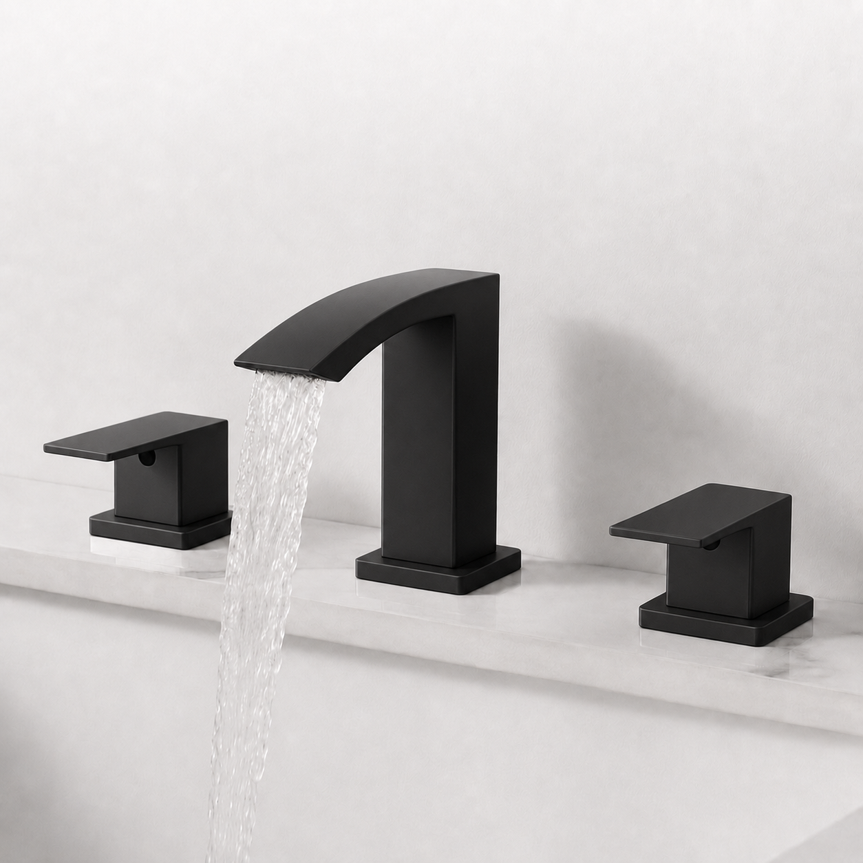 Three-piece matte black bathroom faucet set with a curved spout and two matching handles, shown installed on a white sink with water flowing from the center spout against a light gray wall.