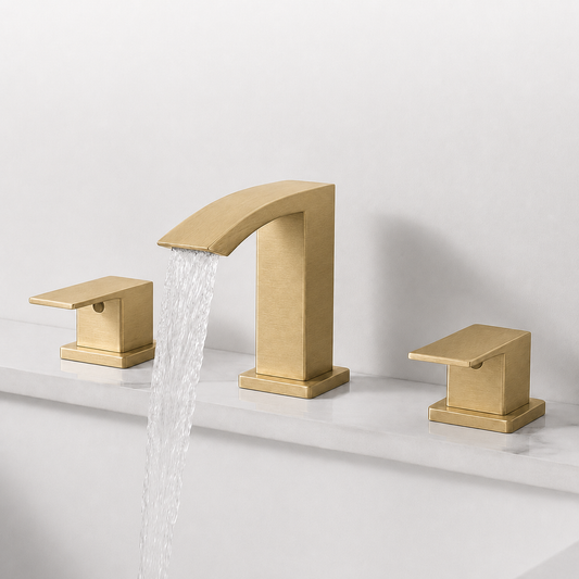 A modern three-hole bathroom faucet set in brushed gold, featuring a central curved spout with water flowing from the spout and two matching lever handles on either side, installed on a white marble sink against a white wall.