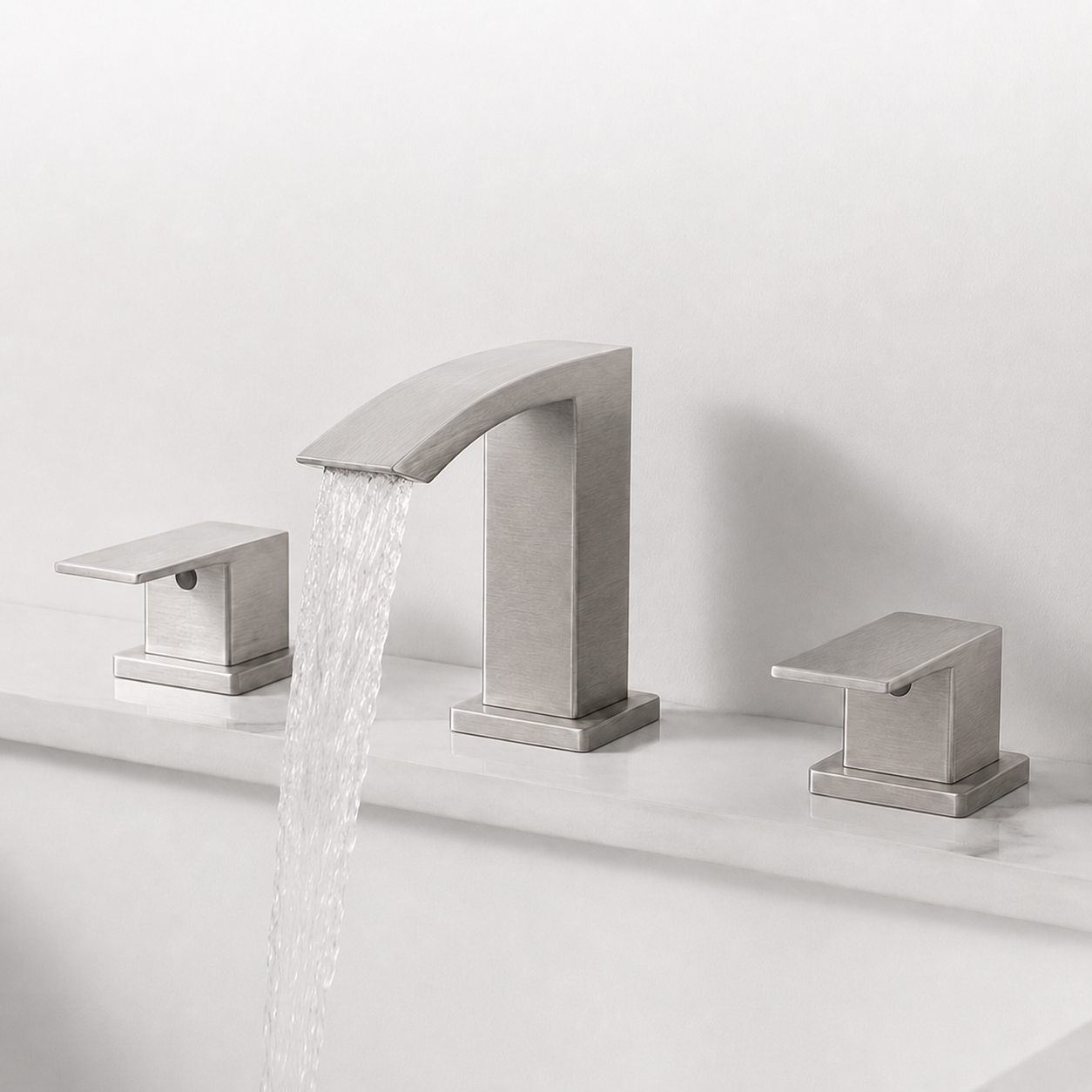 A modern three-hole bathroom faucet set with a brushed silver finish, featuring a central curved spout with running water and two matching lever handles on a white countertop.