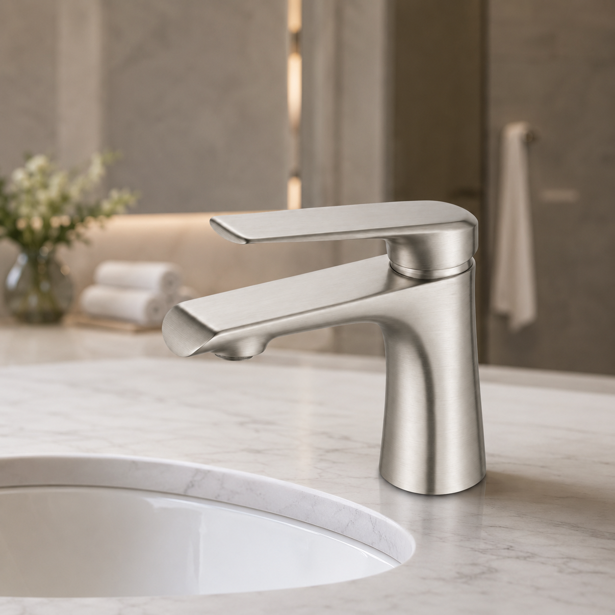 A modern single-handle bathroom faucet in brushed nickel finish, installed on a white marble sink countertop with a blurred bathroom background.