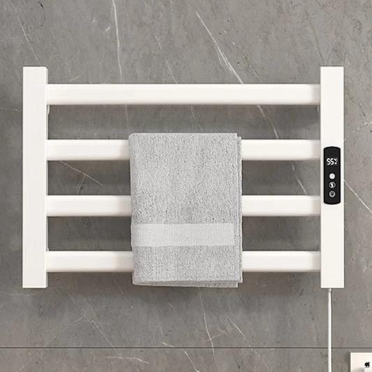 White electric towel warmer rack with power adapter and cord connected to wall outlet