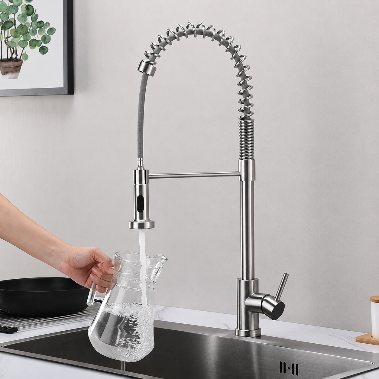 Brushed nickel pull-down kitchen faucet filling a glass water pitcher with single-handle operation
