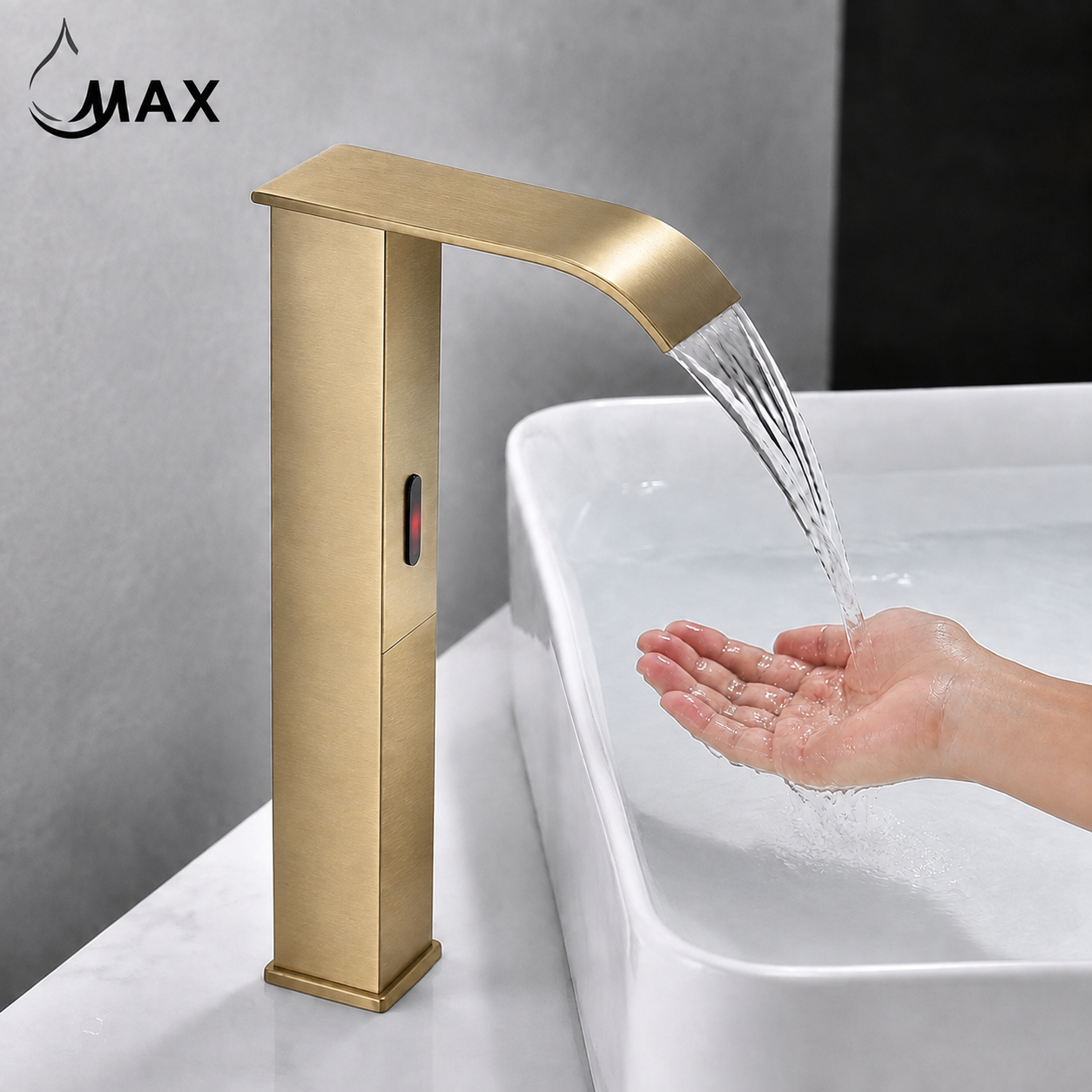 A modern rectangular bathroom faucet in brushed gold/brass finish with water flowing from the spout into a white sink, with a hand reaching under the stream. The word MAX appears in the upper left.