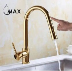 A shiny gold kitchen faucet with a single handle and pull-out sprayer is turned on with water running into a sink, showcasing the product in use.
